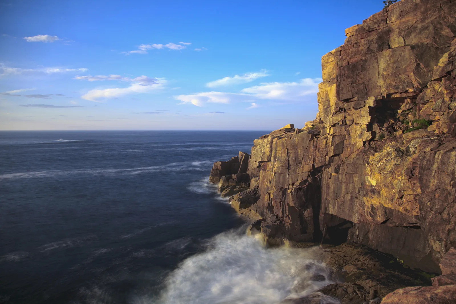The granite face of Otter Cliff in Acadia National Park, above the Atlantic, with surf foaming on the rocks below