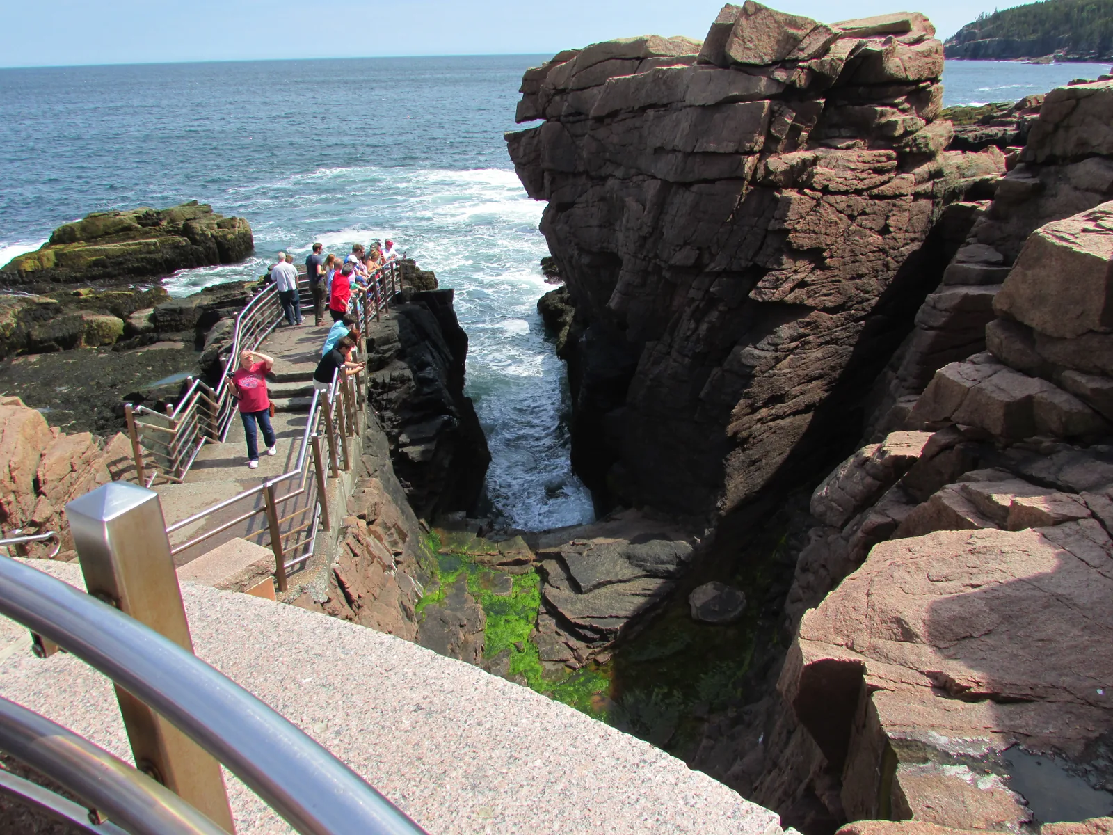 Visitors on the walkway above the Thunder Hole chasm in Acadia National Park, as a wave from the Atlantic crashes in