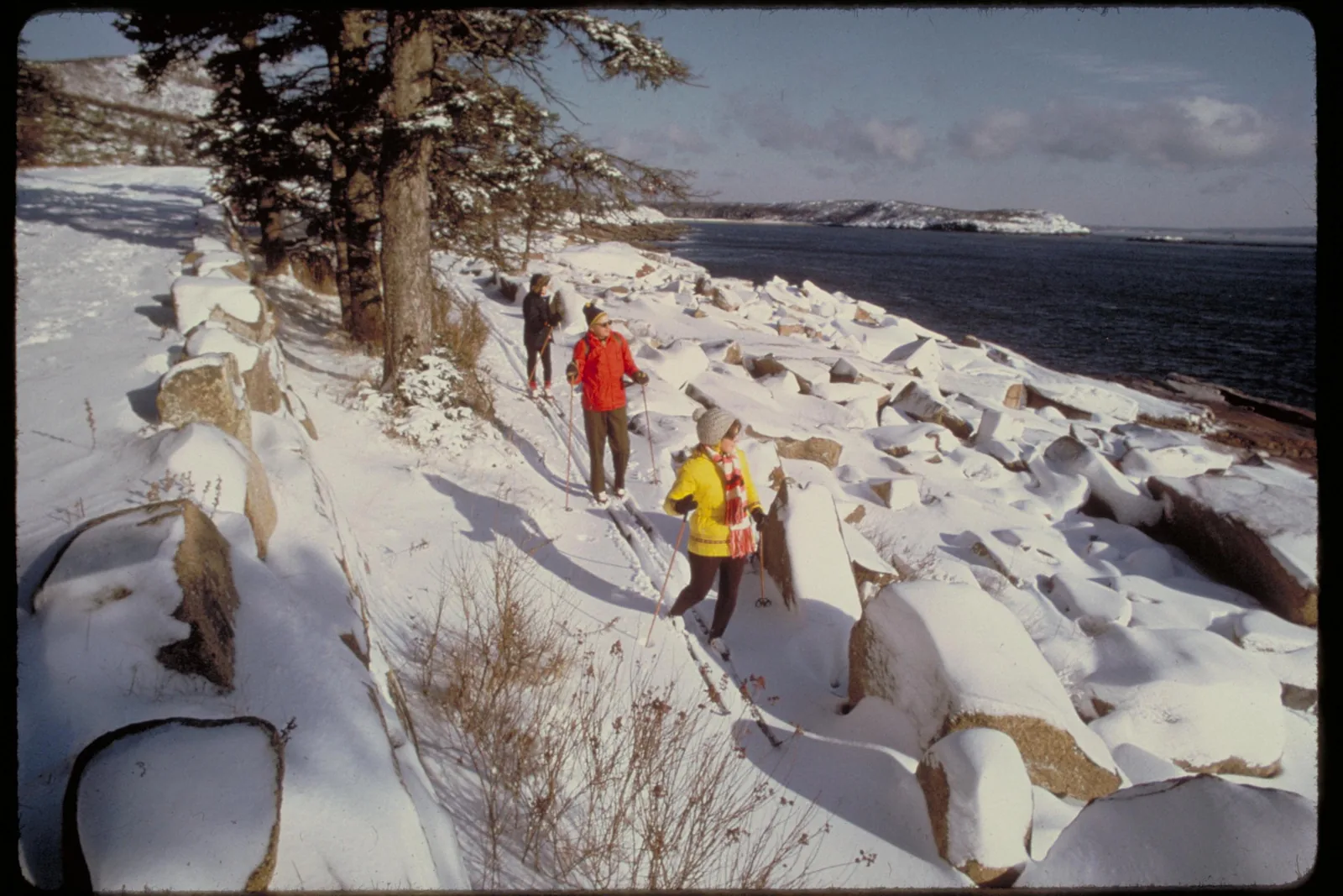 Historic photograph: cross-country skiers between snow-covered granite blocks on the coast of Acadia National Park