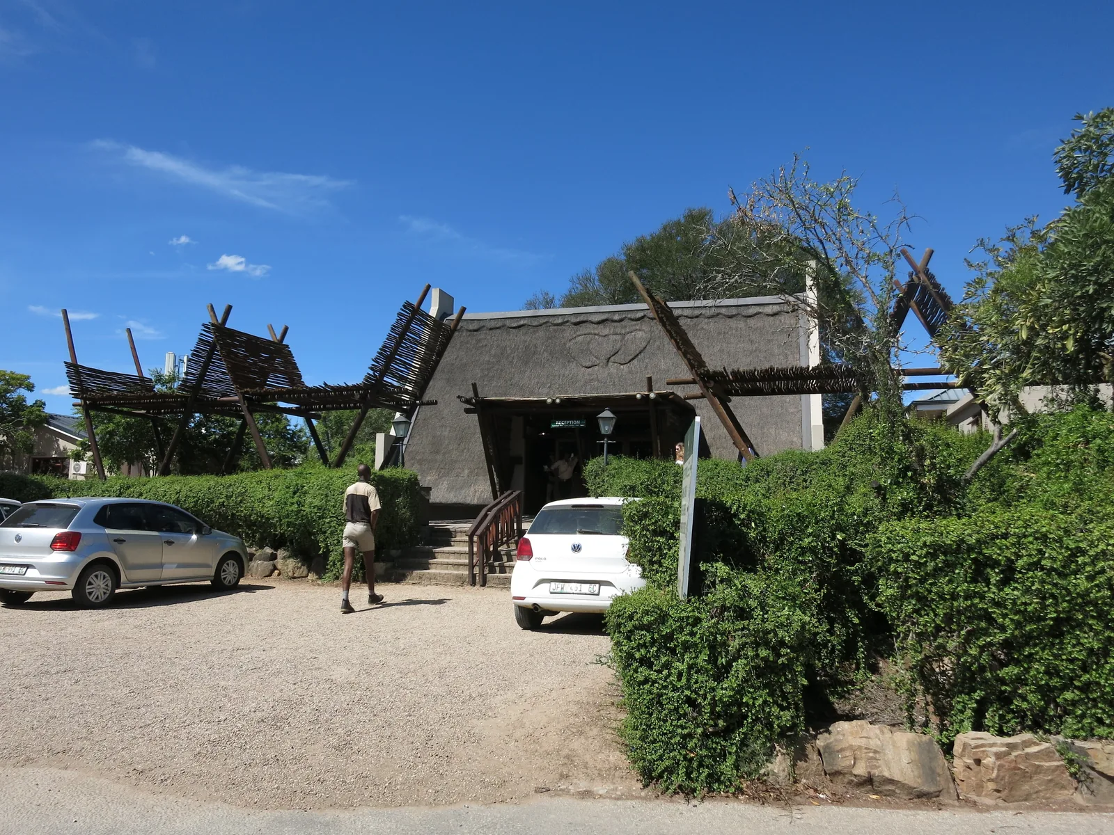 Thatched building in Addo Main Camp in Addo Elephant National Park, cars and bushes in front