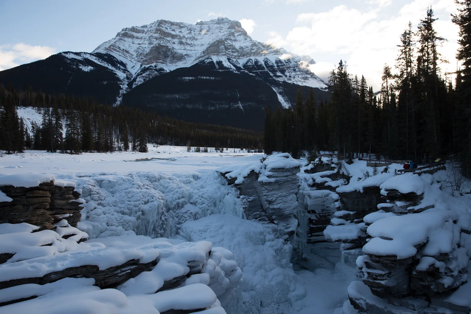 Frozen Athabasca Falls in Jasper National Park under snow, a snow-covered mountain behind