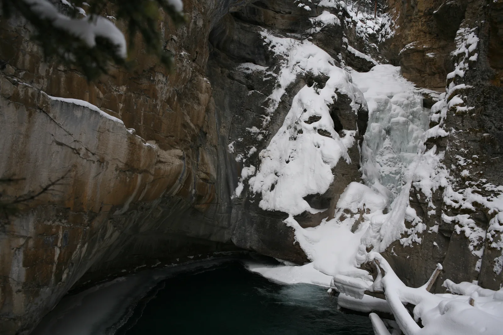 The frozen Lower Falls in Johnston Canyon in Banff National Park in winter, snow on the rocks.