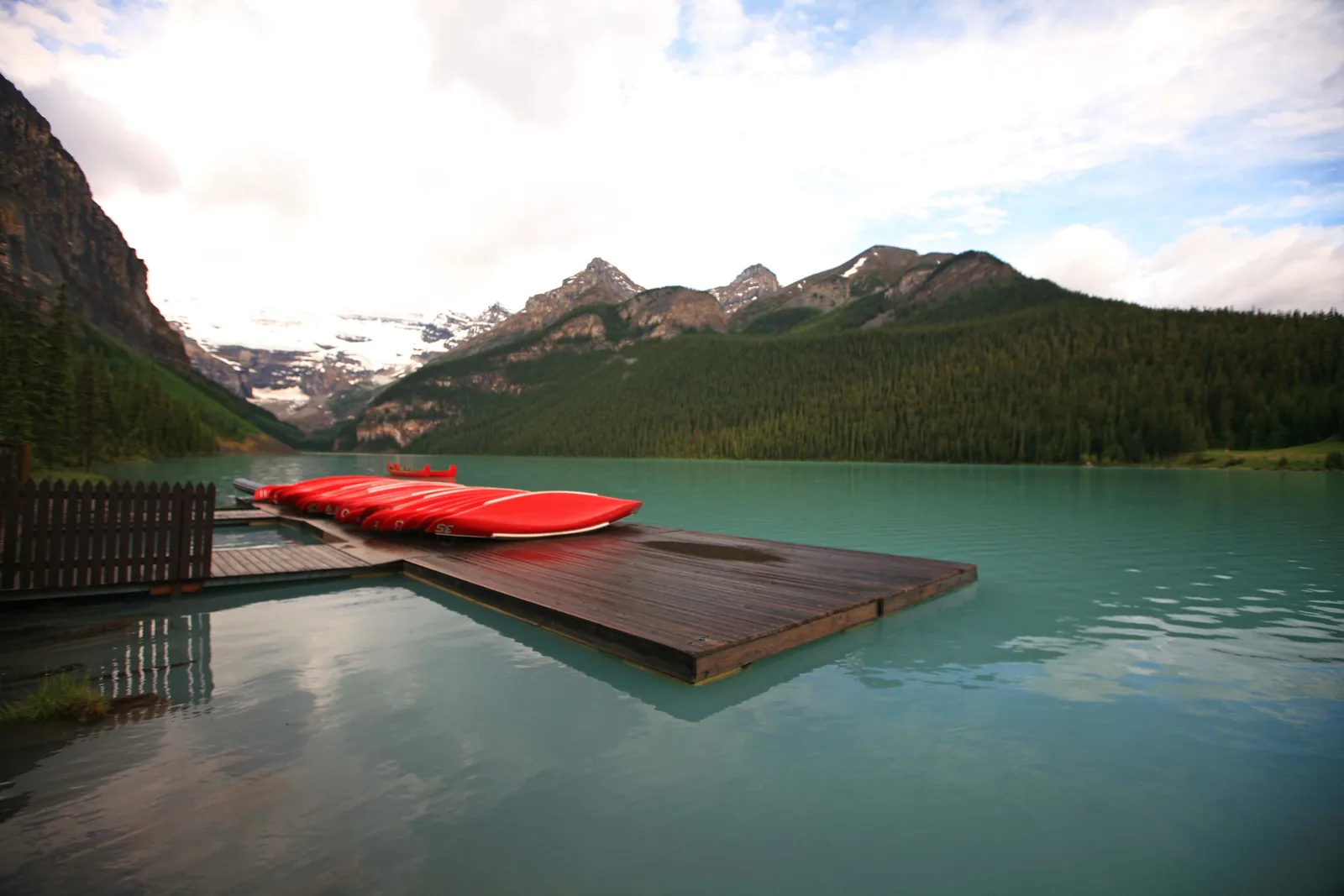 Red canoes in Banff National Park on a dock at turquoise Lake Louise.