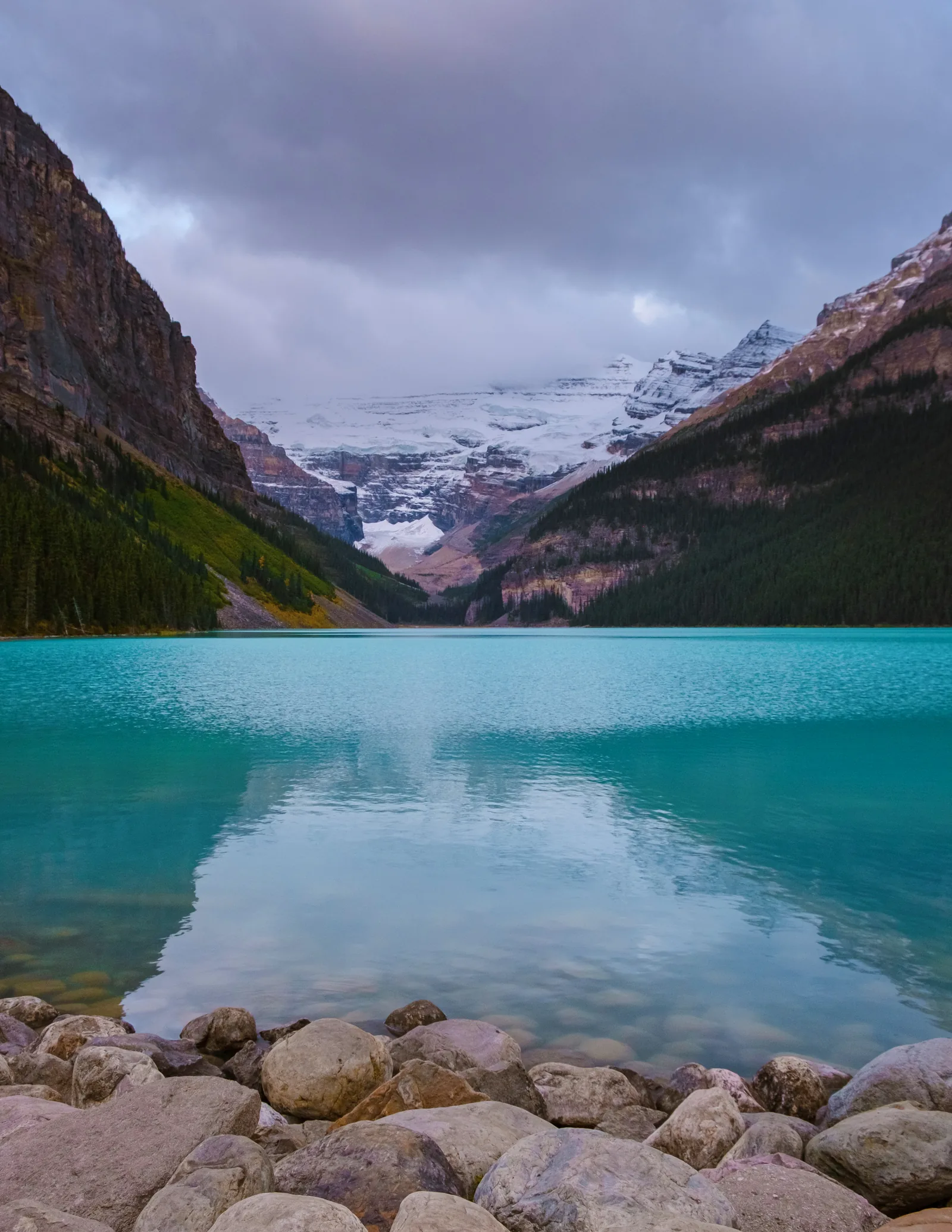Turquoise Lake Louise in Banff National Park below the Victoria Glacier, stones in the foreground.