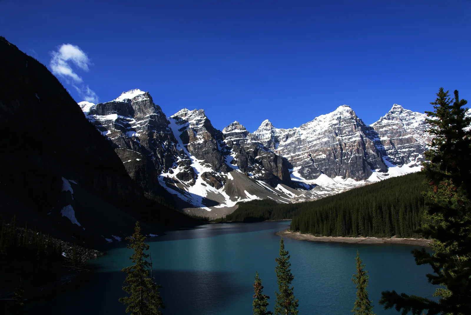 View from the Rockpile in Banff National Park across dark blue Moraine Lake to snowy peaks.