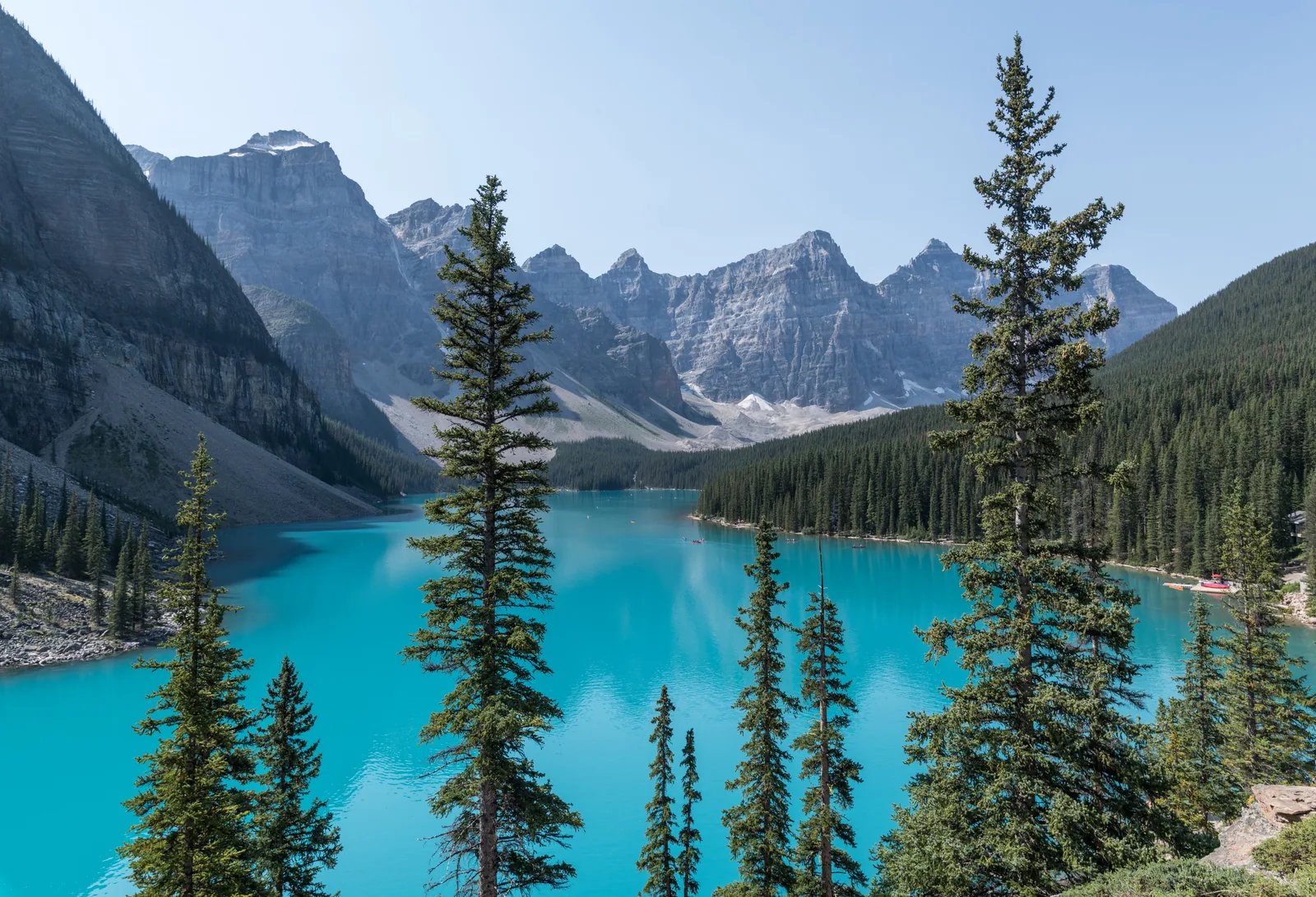 Turquoise Moraine Lake in Banff National Park between conifers, the Ten Peaks behind.