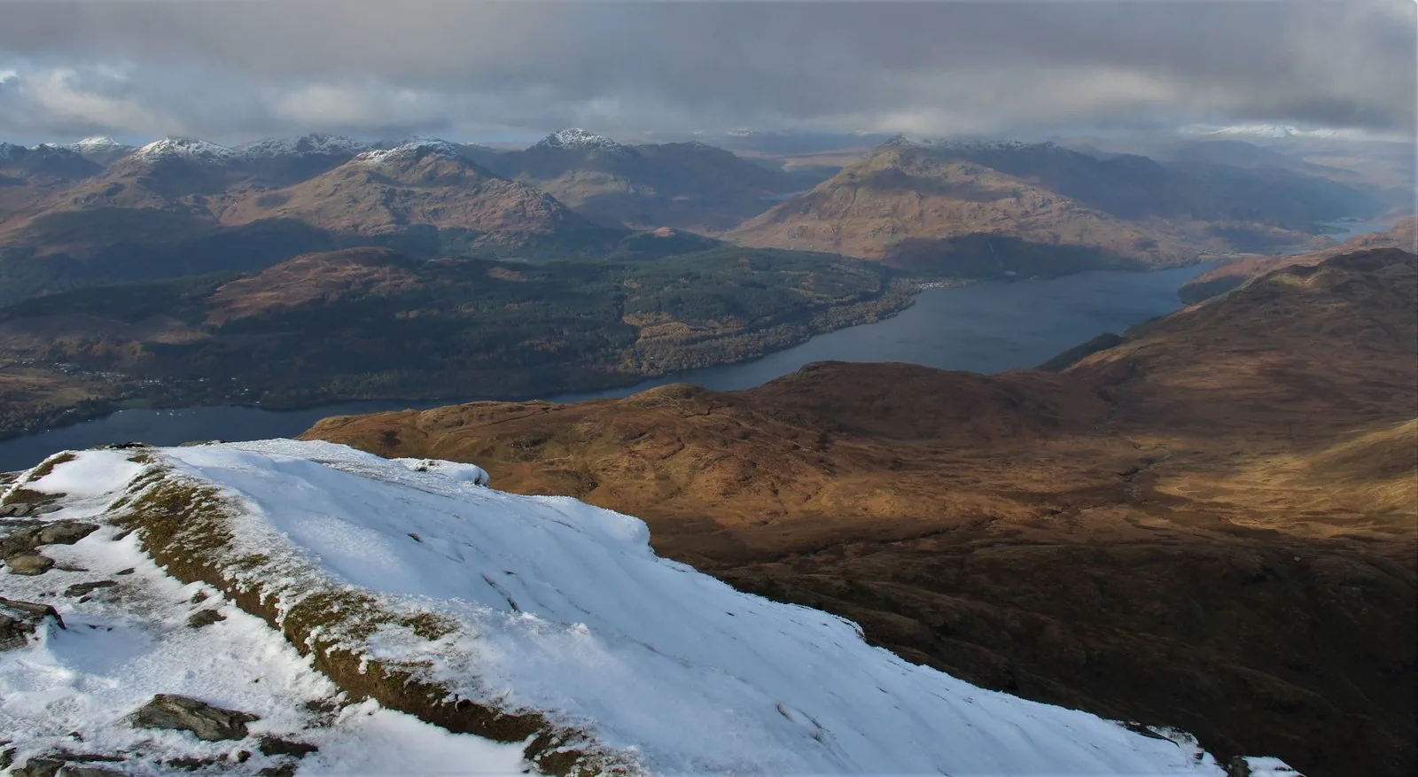 Snowy slope on Ben Lomond looking over Loch Lomond to the mountains of the Arrochar Alps