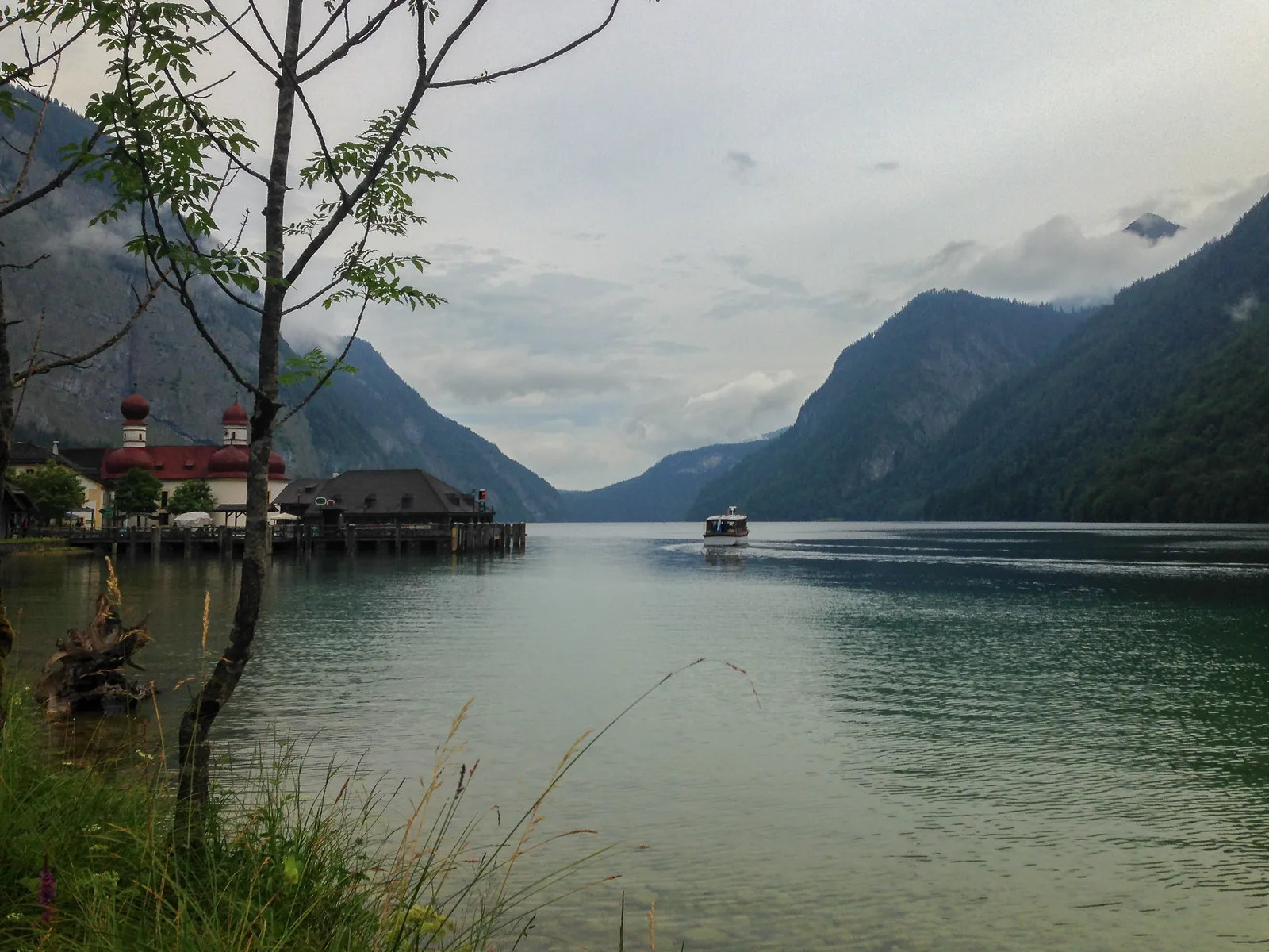 From the shore at St. Bartholomä in Berchtesgaden National Park, the view goes north across Lake Königssee as an excursion boat departs