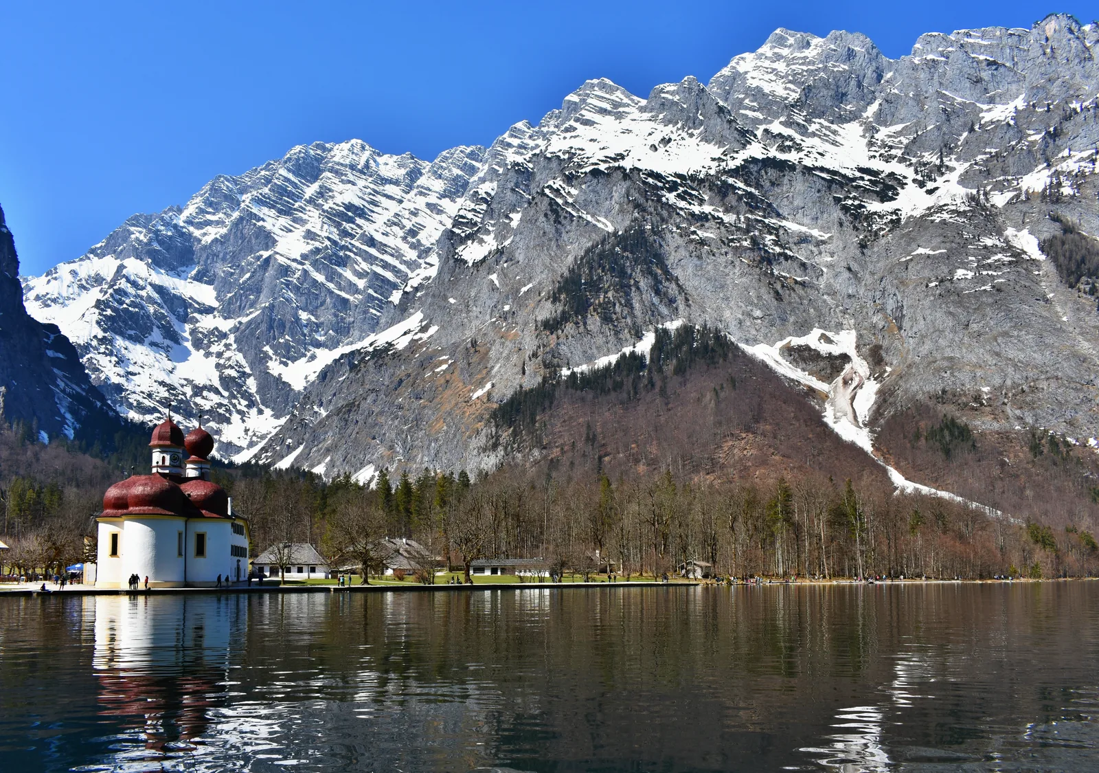The red-domed pilgrimage church of St. Bartholomä on Lake Königssee in Berchtesgaden National Park, below the snow-covered Watzmann East Face