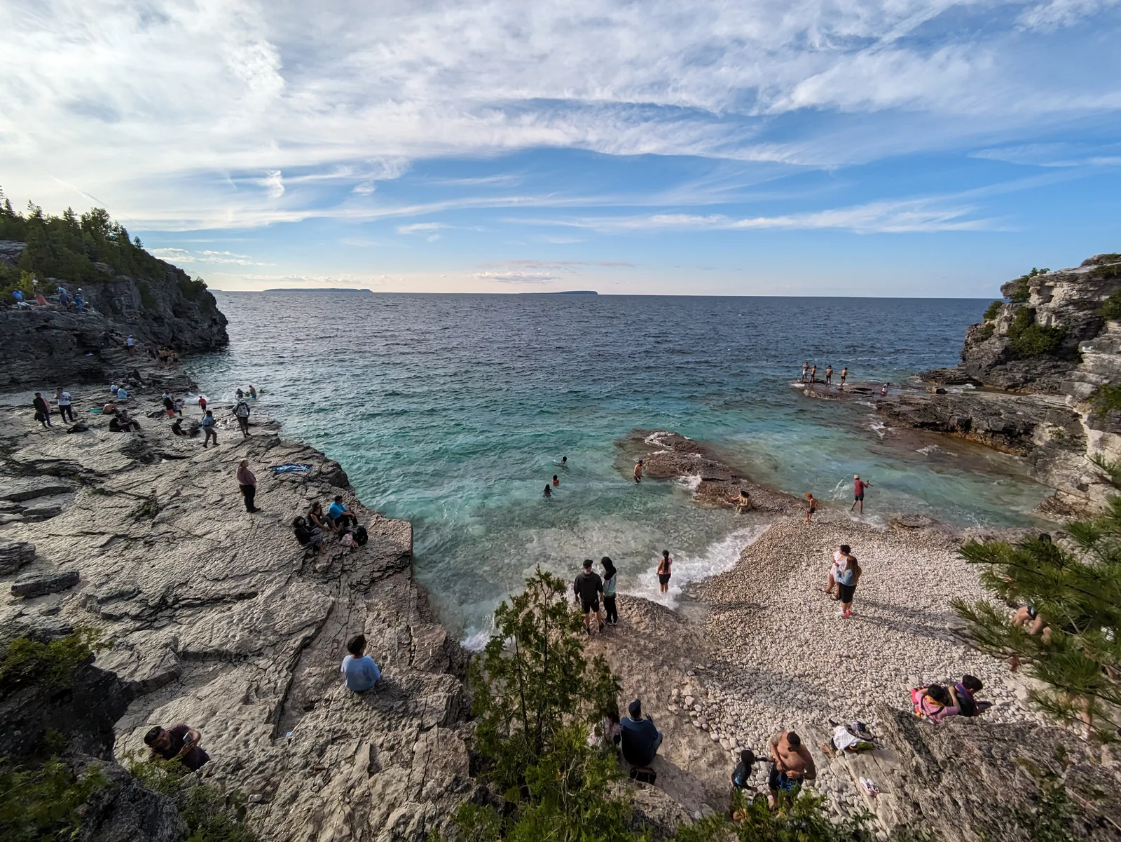 Indian Head Cove in Bruce Peninsula National Park: turquoise water in a cove between white limestone terraces, with many visitors sitting on the rocks and swimming