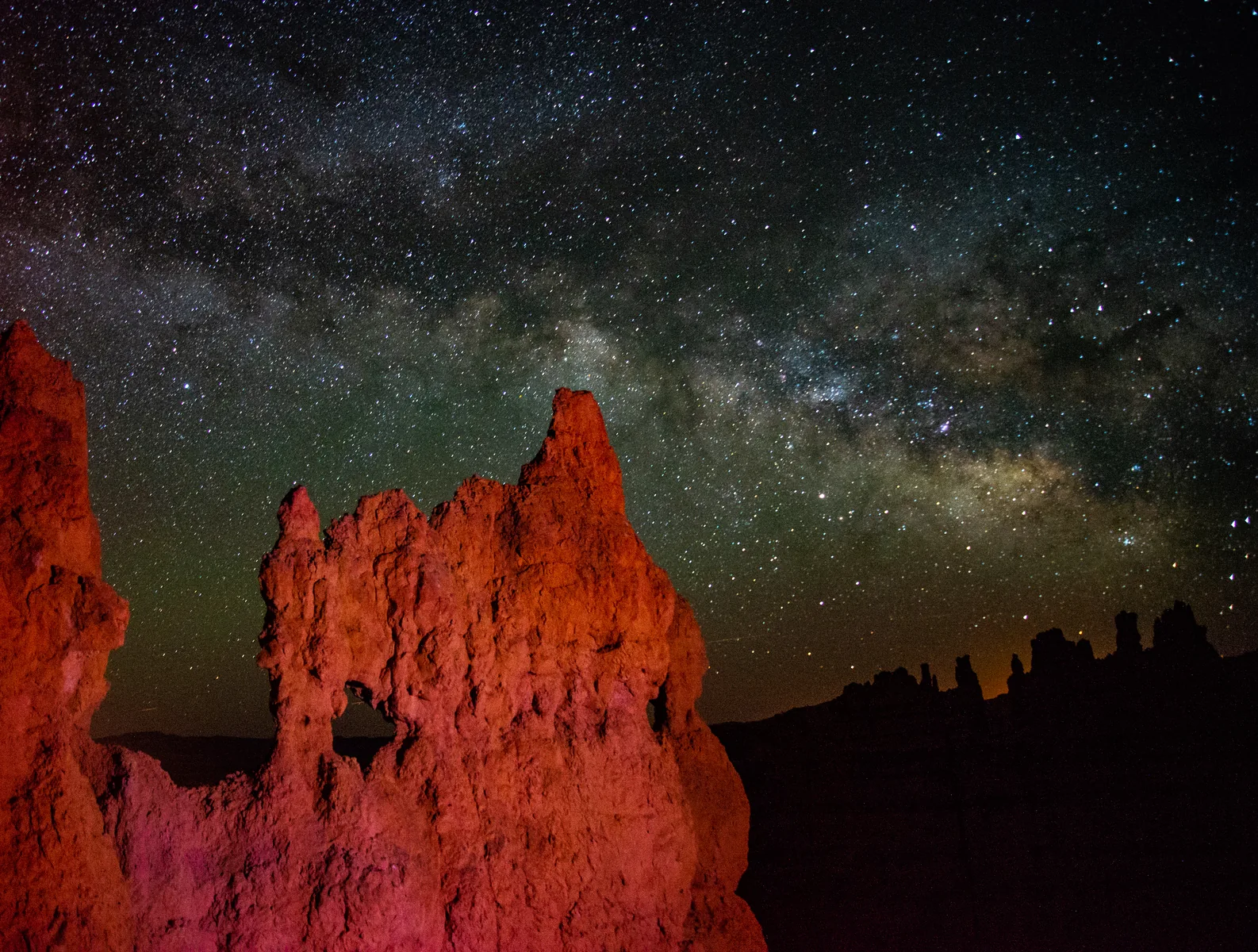 The Milky Way above a lit hoodoo on the Navajo Trail in Bryce Canyon National Park