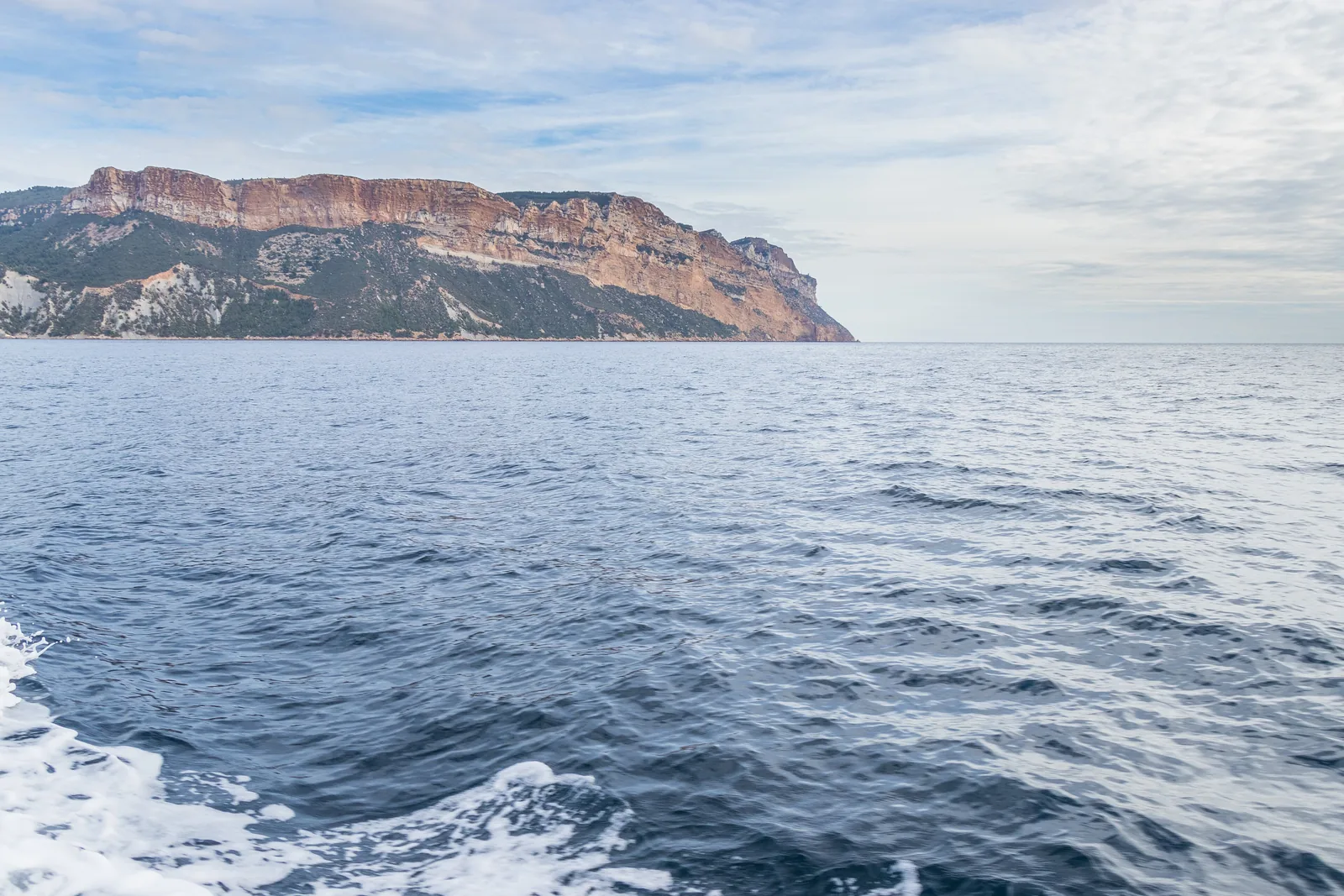 Cap Canaille in Calanques National Park seen from the sea off Cassis: reddish cliffs above blue water