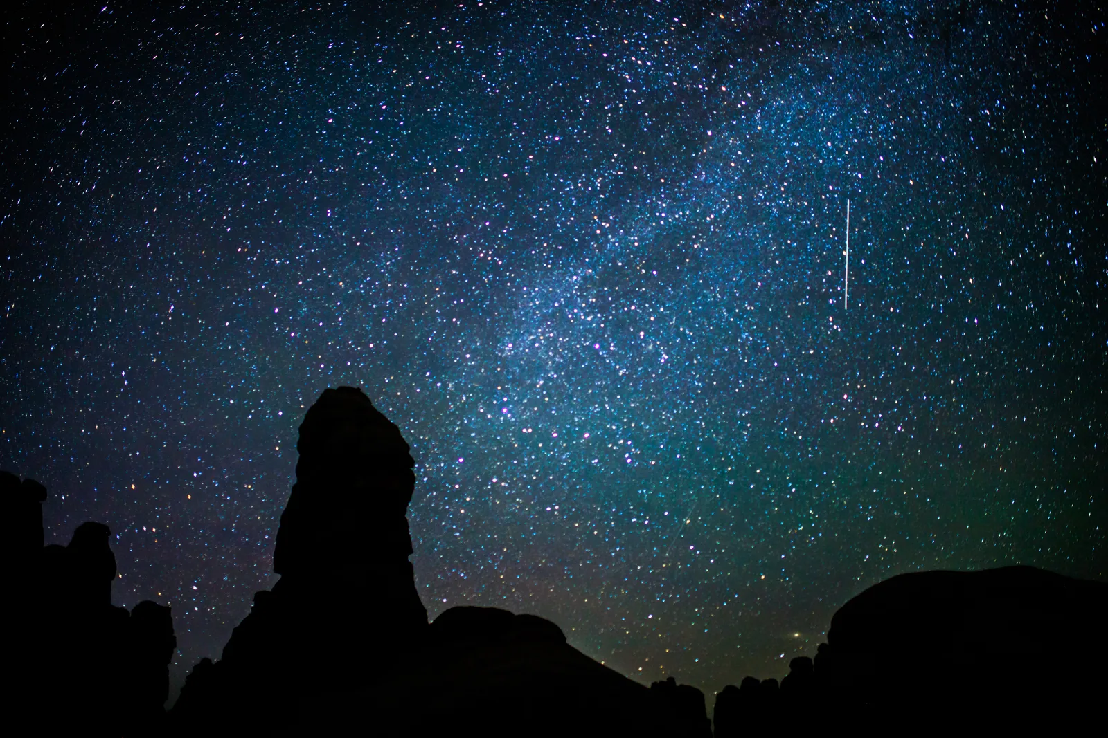 Starry sky with the Milky Way above the dark silhouettes of the rock spires in Chesler Park, Canyonlands National Park