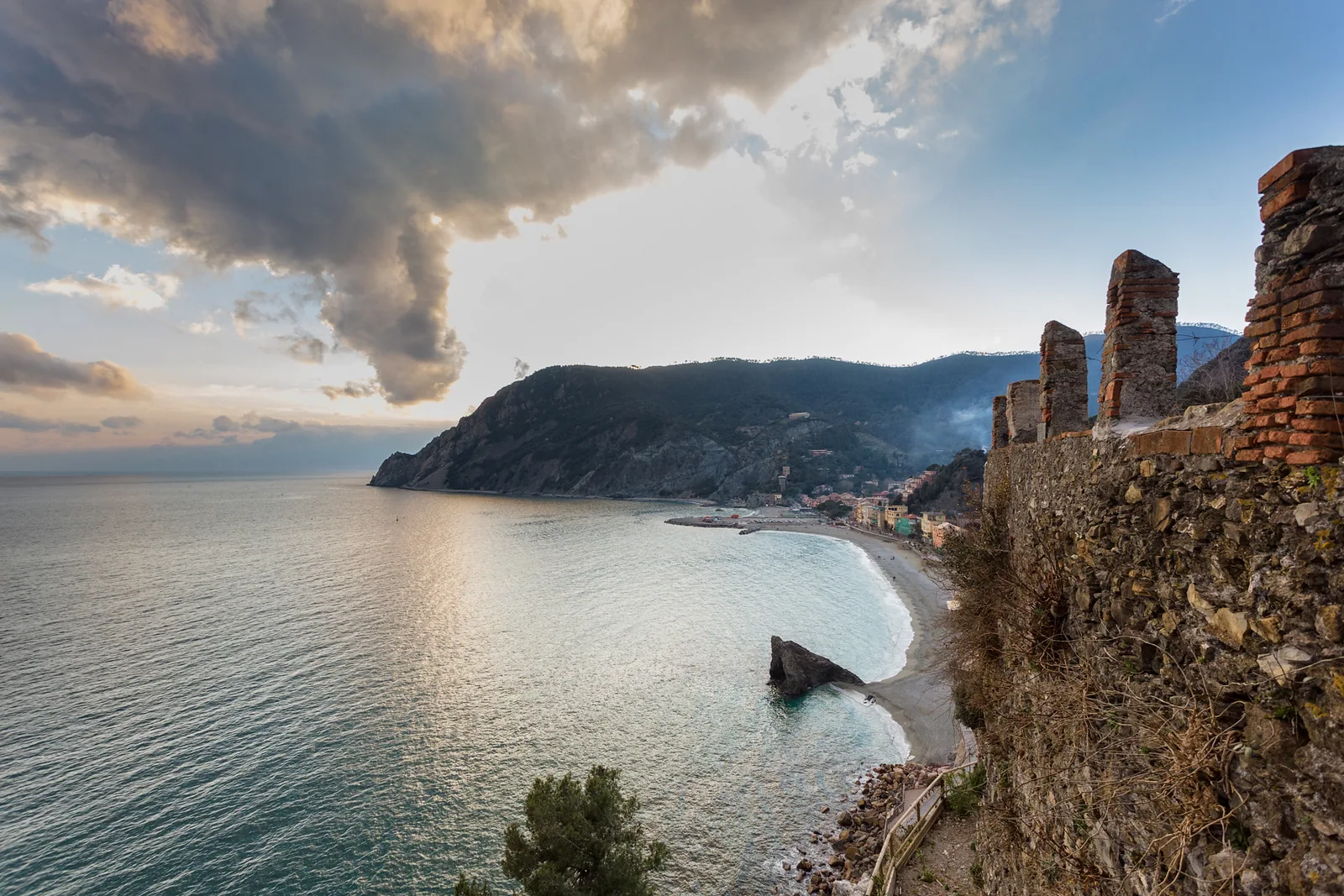 View from Monterosso al Mare in Cinque Terre National Park across the bay to Punta Mesco, with old walls on the right
