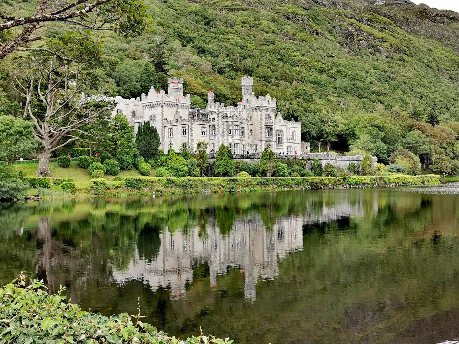 Kylemore Abbey near Connemara National Park on the shore of a lake in front of a wooded slope