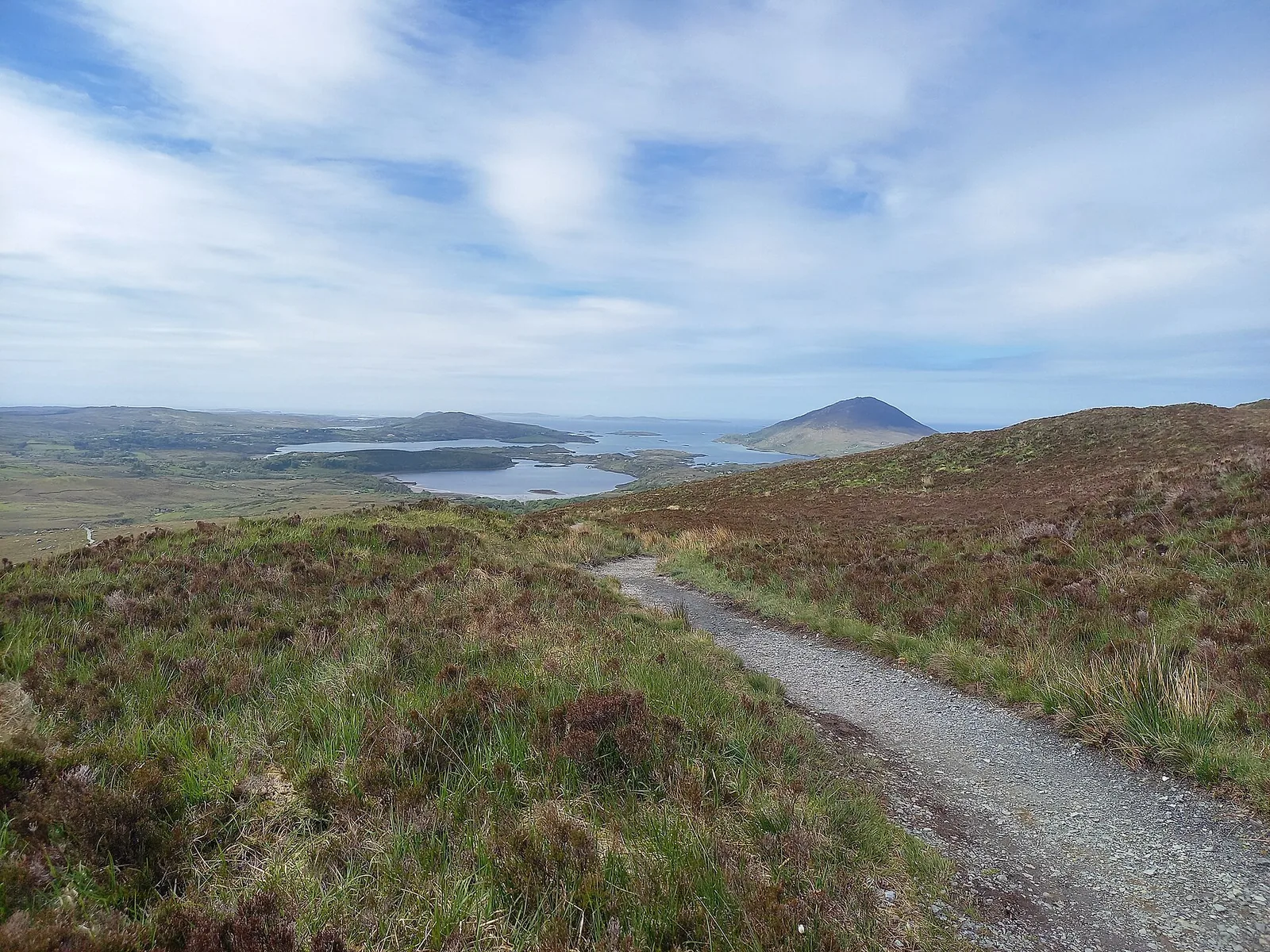 View from Diamond Hill in Connemara National Park over green slopes, lakes and hills on a sunny day