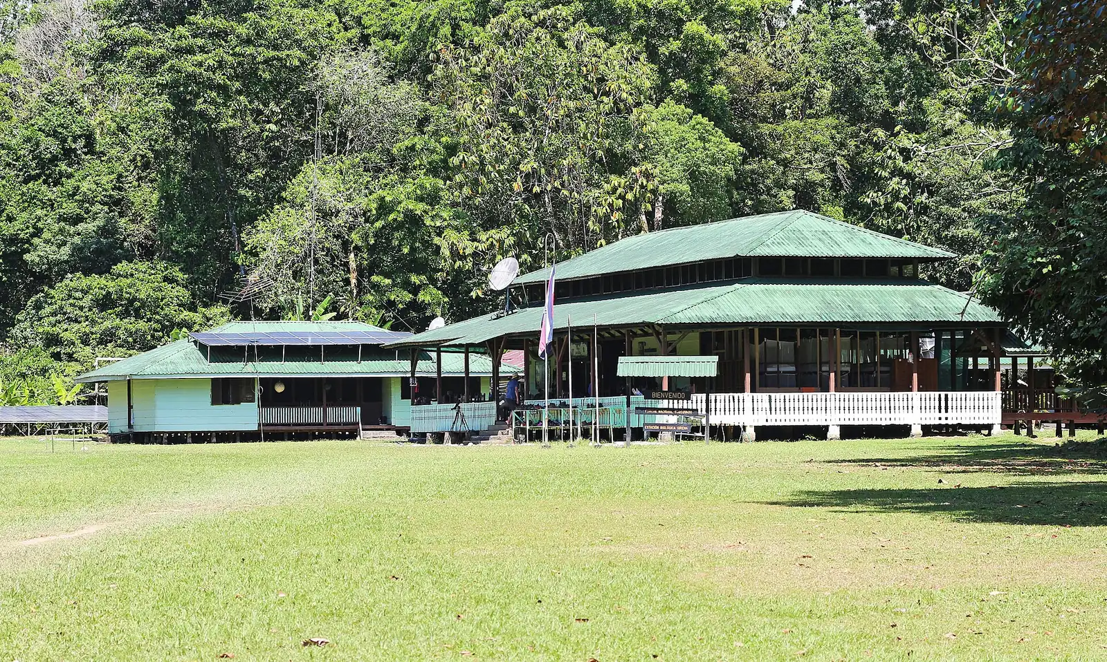 The wooden Sirena ranger station in Corcovado National Park with a green roof on a lawn in front of dense rainforest