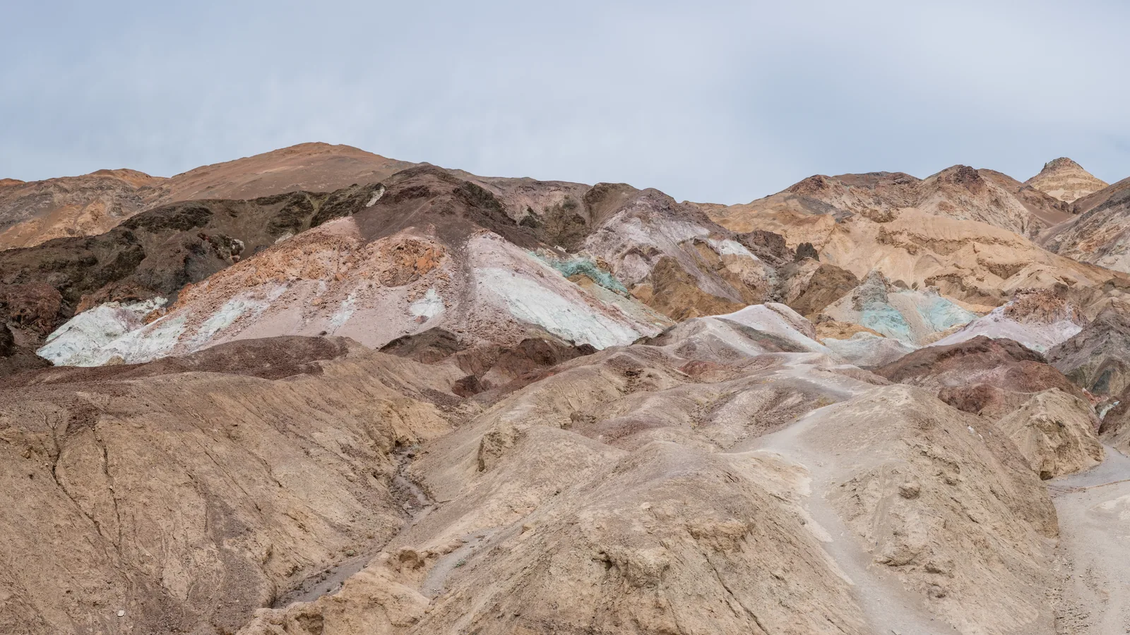Hills in pink, turquoise, ochre and brown at Artists Palette in Death Valley National Park under an overcast sky