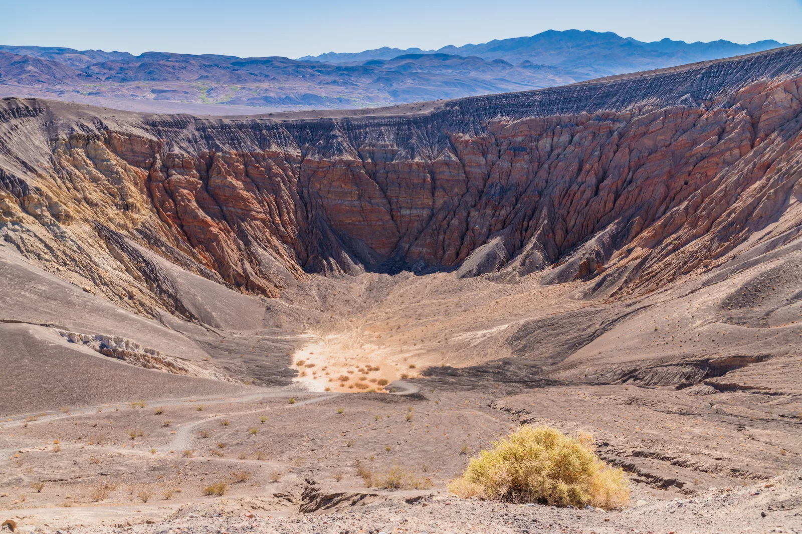 Ubehebe Crater in Death Valley National Park from above: steep inner walls striped red and brown, with a pale patch on the flat floor