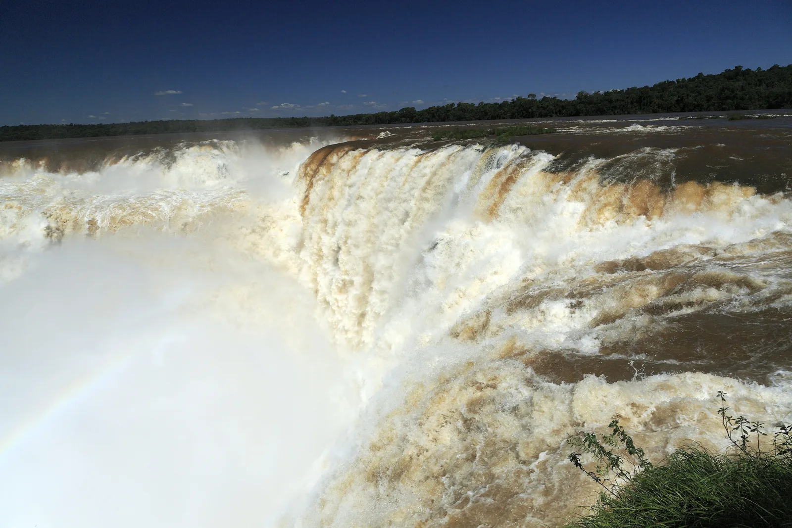 Brown masses of water plunge into the south-east corner of the Devil's Throat, with spray hiding the bottom of the gorge