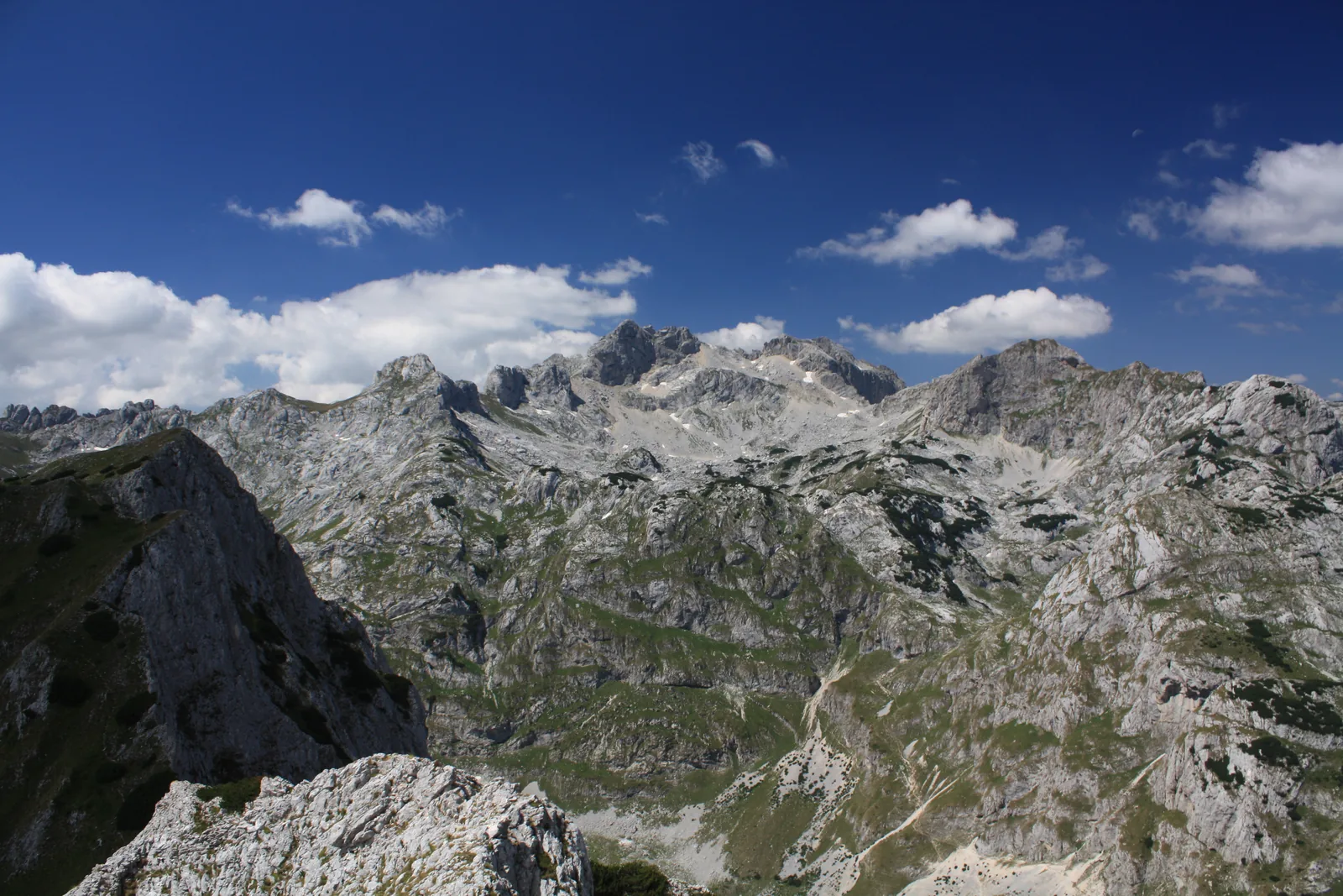 View across a jagged, pale limestone range in Durmitor National Park with sharp ridges and hollows under a deep blue sky