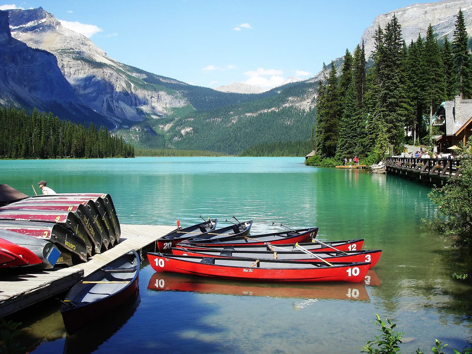 Red rental canoes at the dock on Emerald Lake in Yoho National Park, the lodge and mountains behind the green water.