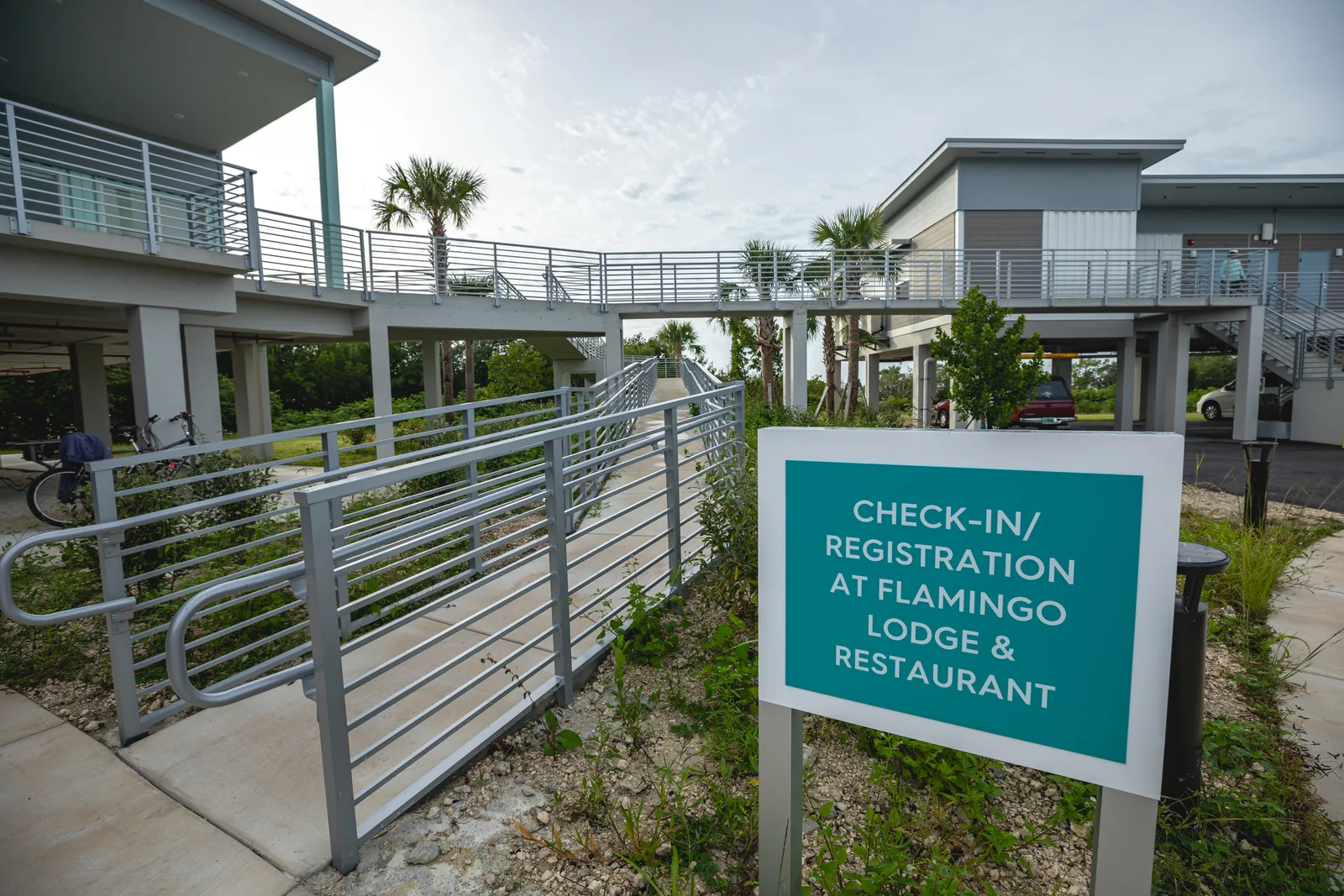 New buildings of the Flamingo Lodge in Everglades National Park on stilts with ramps, in front a turquoise sign for lodge and restaurant check-in