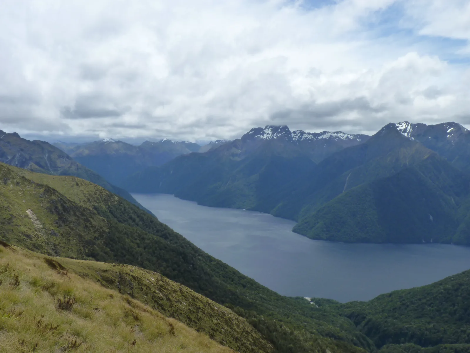 From the Kepler Track in Fiordland National Park the view drops over tussock slopes to the South Fiord of Lake Te Anau and the Murchison Mountains