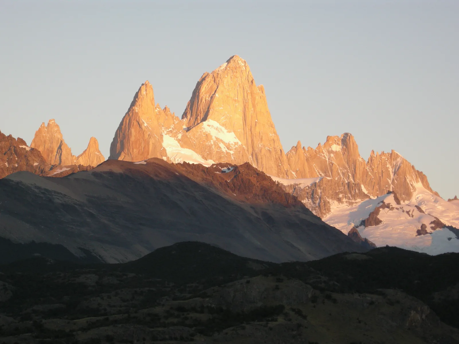 The granite spires of Fitz Roy in Los Glaciares National Park in the red light of dawn, seen from the Laguna Capri campsite