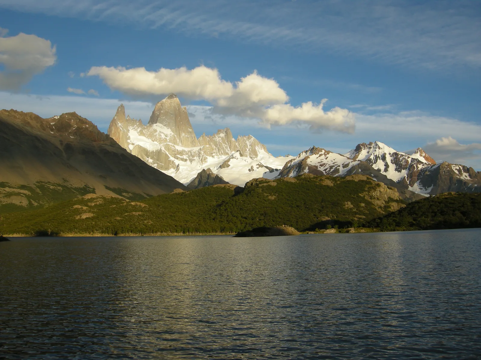 The east face of the Fitz Roy massif in Los Glaciares National Park above Laguna Capri, wooded shores in front