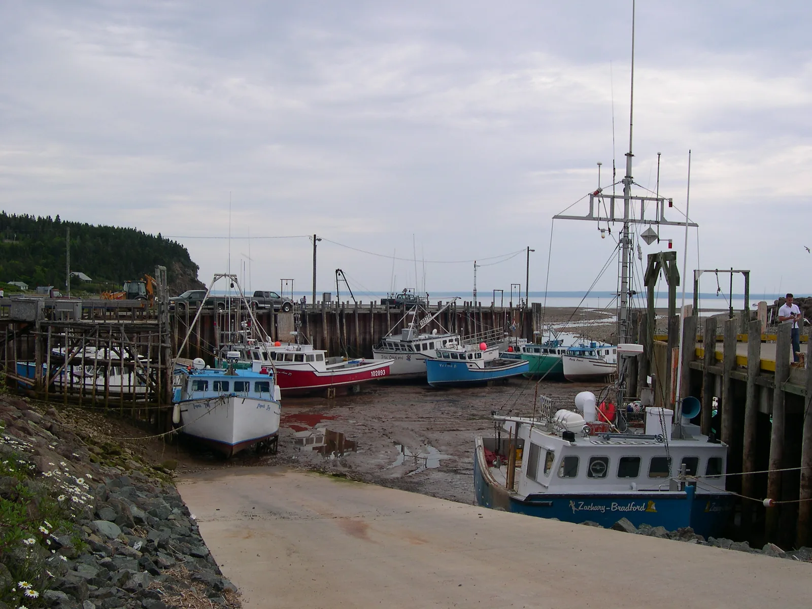 Alma harbour at low tide: fishing boats stand upright on the dry harbour bottom, the quay wall towering beside them