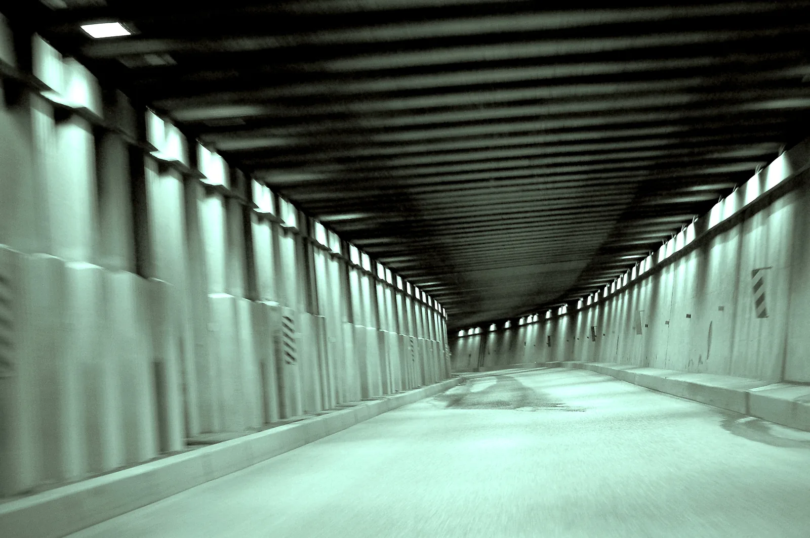 View from a moving car through a concrete avalanche shed at Rogers Pass in Glacier National Park in Canada, the lights streaking past