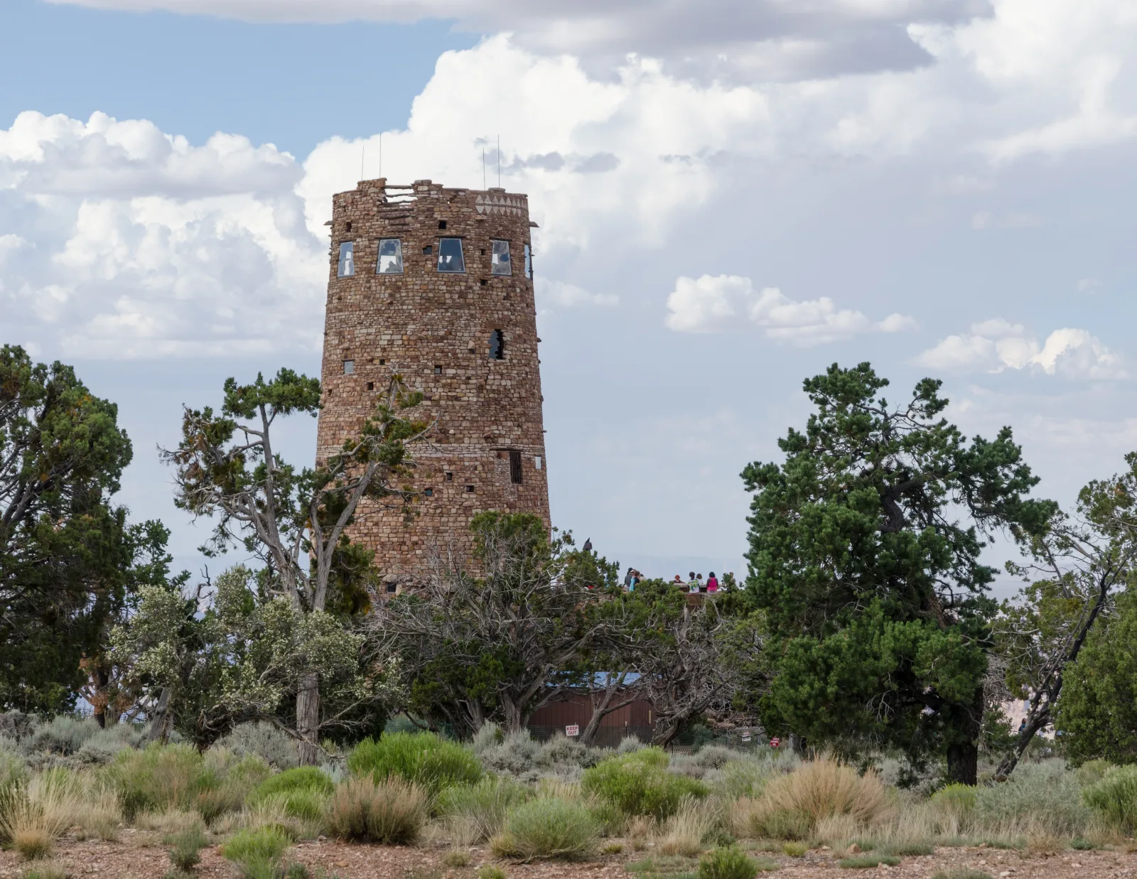 The stone Desert View Watchtower in Grand Canyon National Park rises above juniper bushes on the eastern rim