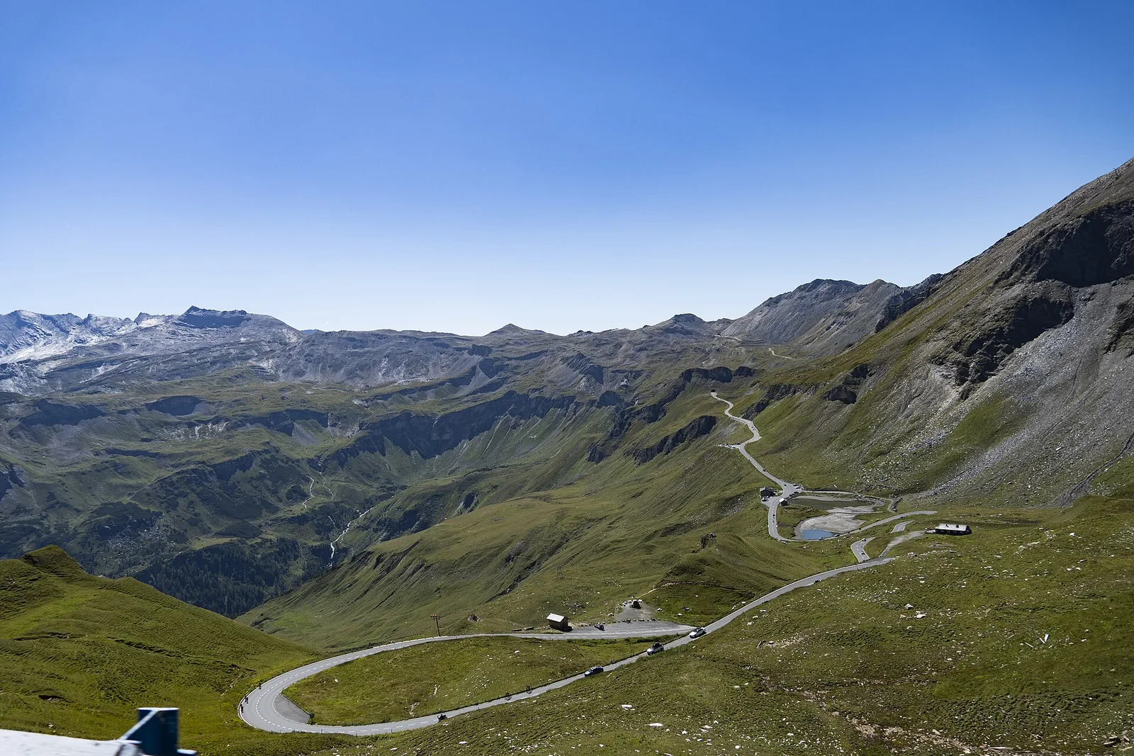 The Grossglockner High Alpine Road in wide curves across green alpine pastures, the Fuscher Lacke in the background