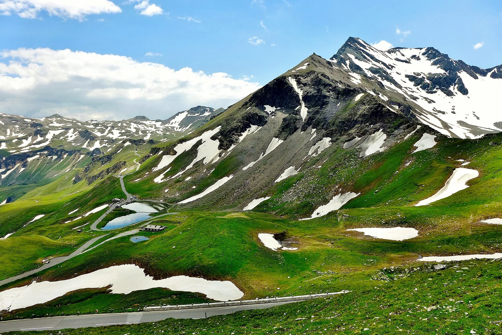 Green slopes with patches of snow and peaks of the Hohe Tauern, taken near the Fuscher Törl on the Grossglockner High Alpine Road