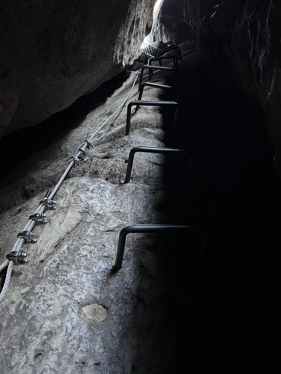 Iron rungs and steel cable in the narrow rock crevice of the upper section of the Häntzschelstiege in the Affensteine