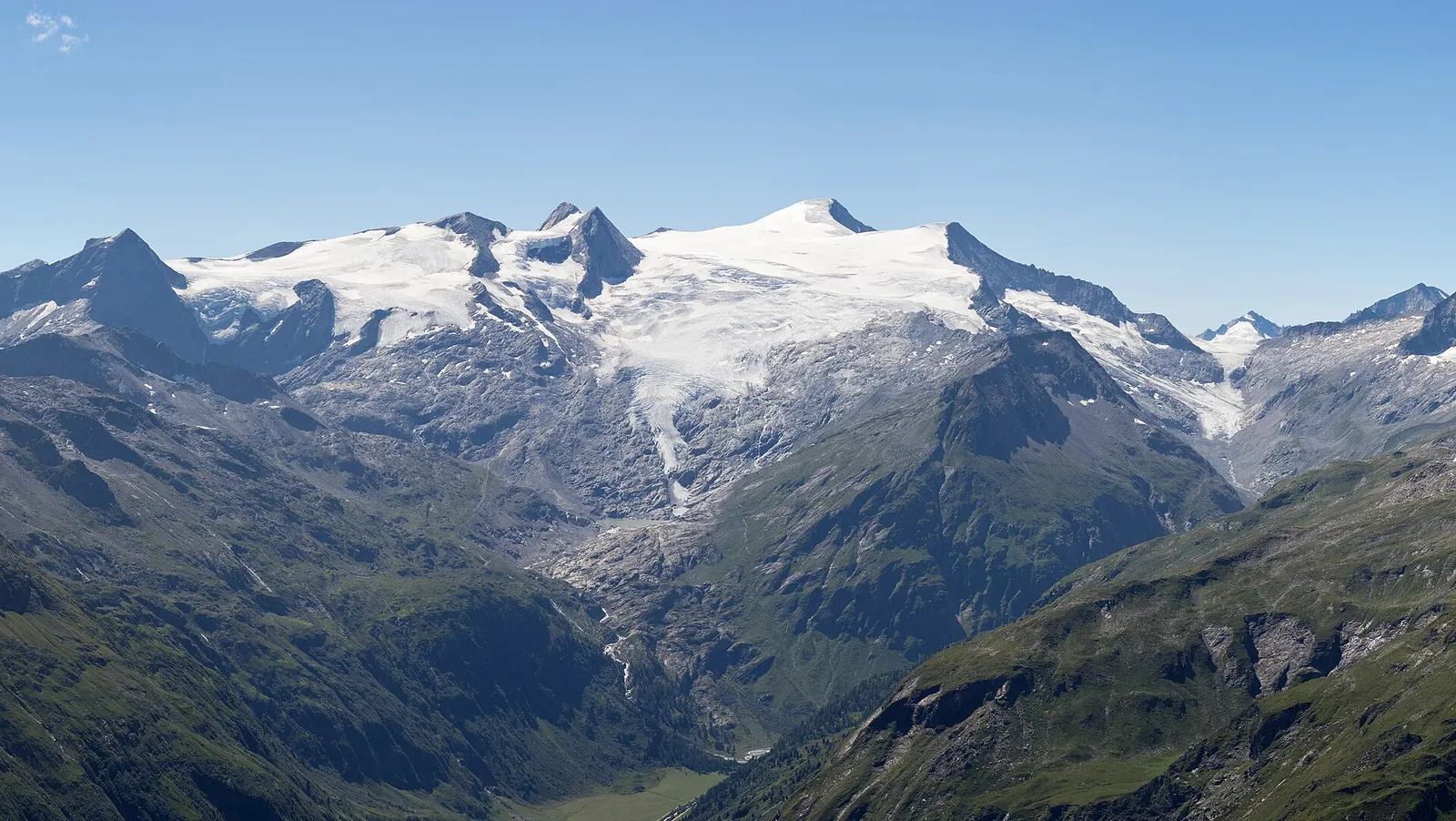 The glaciated massif of the Grossvenediger in Hohe Tauern National Park with several firn summits above green and rocky valley slopes