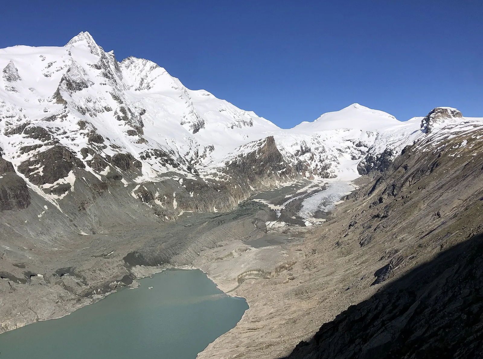 The snow-covered Grossglockner and the Johannisberg in Hohe Tauern National Park above the Pasterze, whose debris-covered glacier tongue ends in a turquoise lake