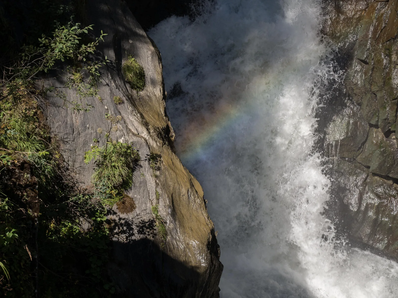 The Umbal Falls in Hohe Tauern National Park plunge through a narrow rocky gorge, a rainbow in the spray
