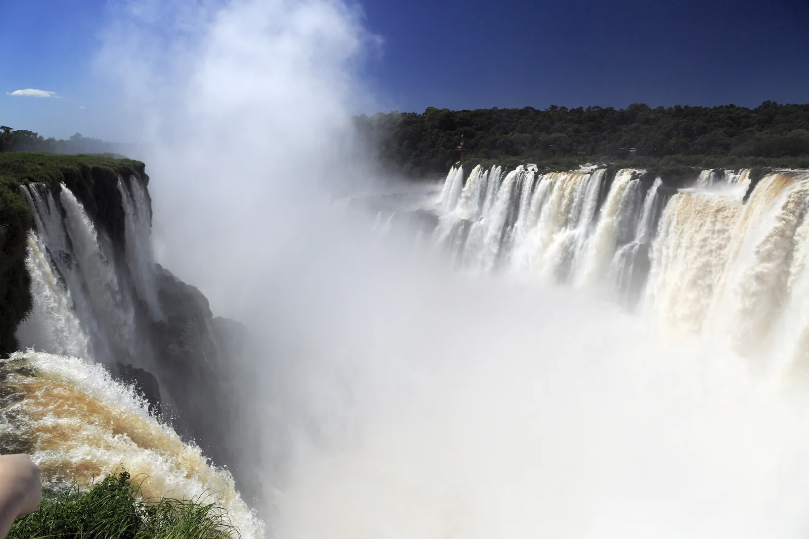 Spray rises from the horseshoe-shaped Devil's Throat in Iguazú National Park, with broad white waterfalls plunging over the edge on the right