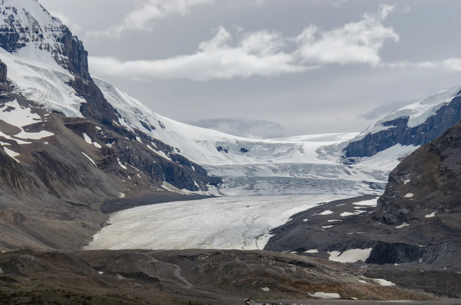 The tongue of the Athabasca Glacier in Jasper National Park between dark mountainsides