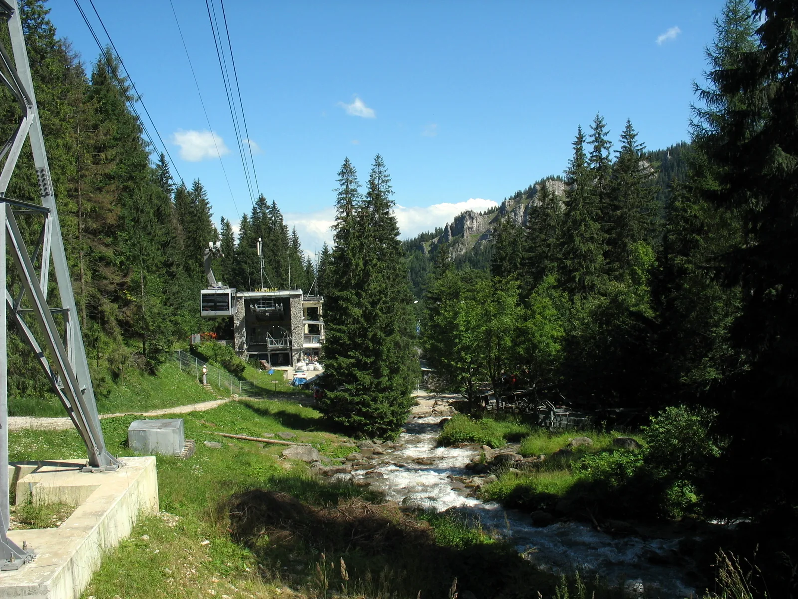 The lower station of the Kasprowy Wierch cable car in Kuźnice by the Bystra stream, with a cable car tower and spruce forest in front