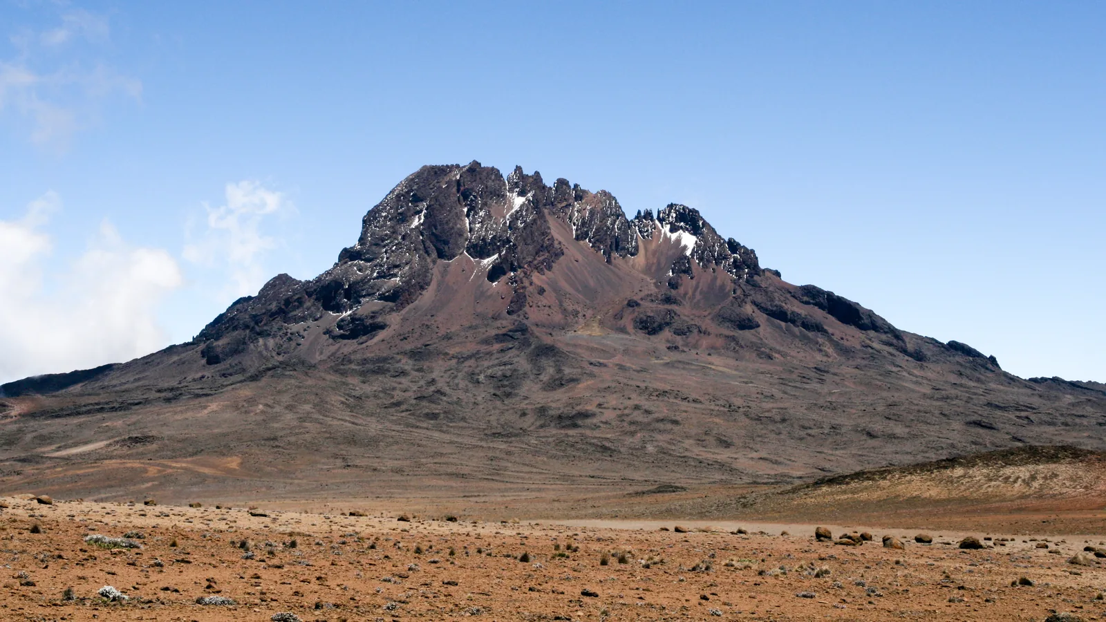 The jagged Mawenzi in Kilimanjaro National Park above the barren alpine desert under a blue sky