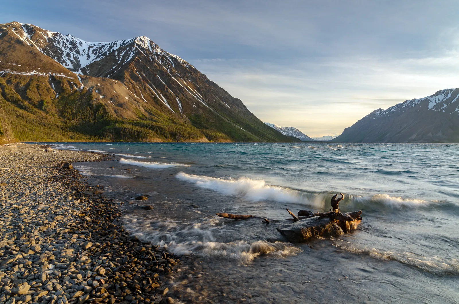 Evening light on Kathleen Lake in Kluane National Park, waves on the gravel shore, behind it the steep flanks of the Kluane Range