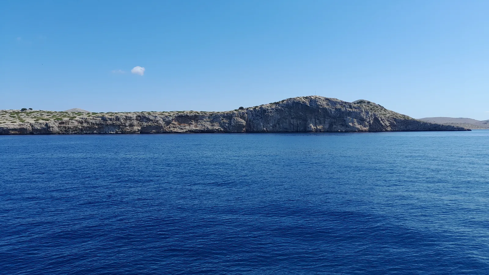 Island in Kornati National Park with a pale rock edge above a deep blue sea.