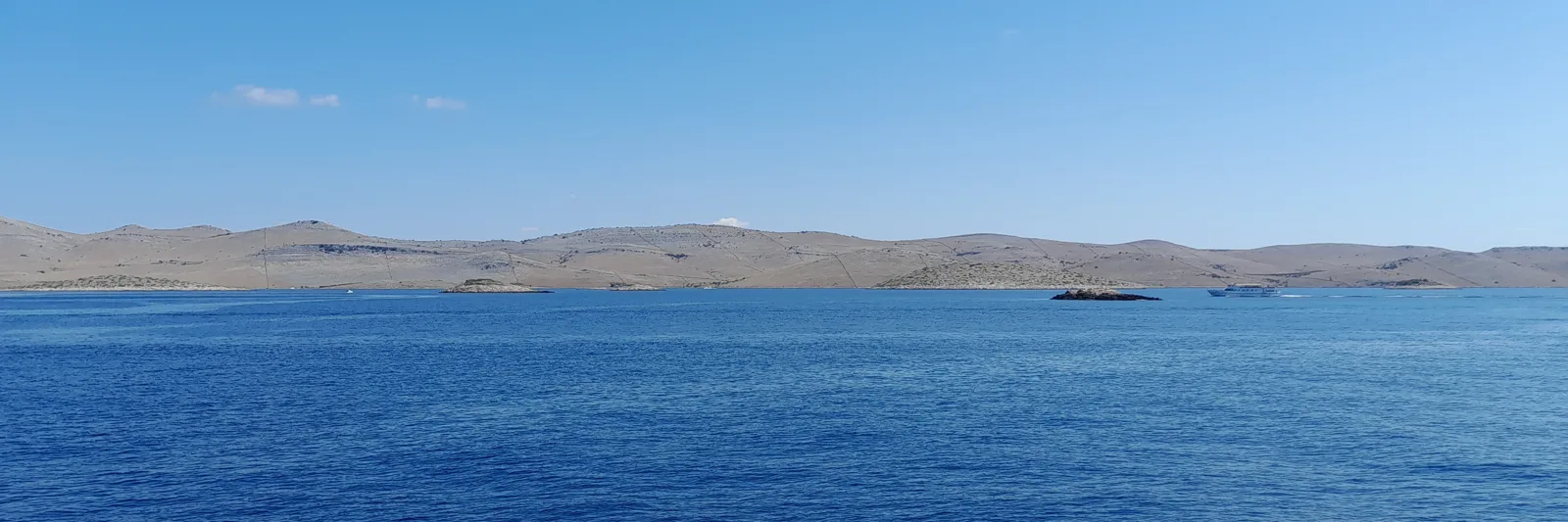 Chain of low karst islands around Kornat in Kornati National Park, in a deep blue sea