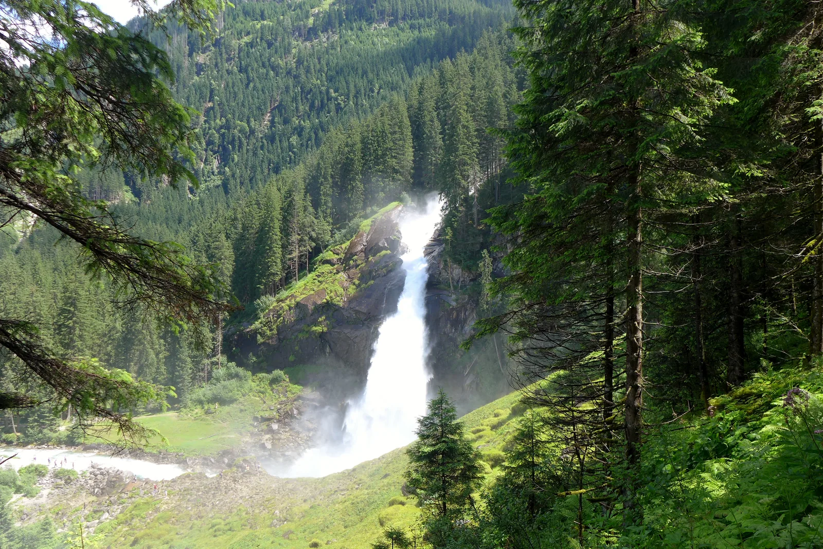 The Krimml Waterfalls plunge between wooded slopes into the valley, seen from the foot of the falls in Hohe Tauern National Park