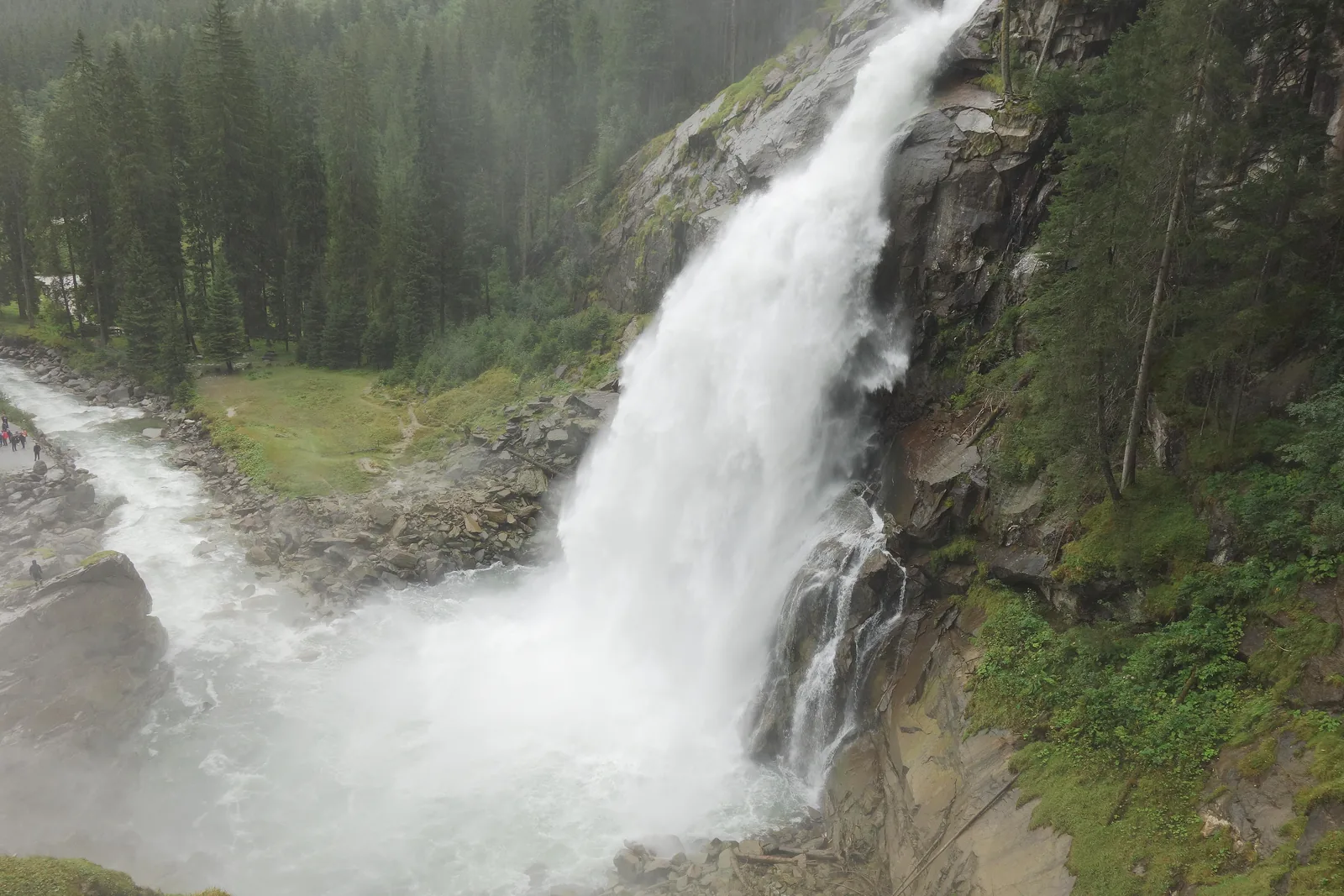 White water of the Krimml Waterfalls shoots over dark rock into a cloud of spray, taken from the waterfall trail