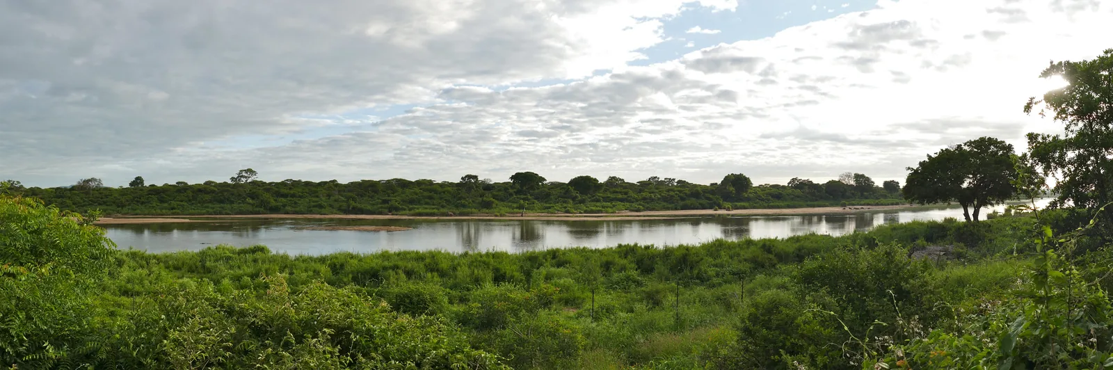Wide view across the Sabie River in Kruger National Park with sandbanks and green riverside bush under a cloudy sky