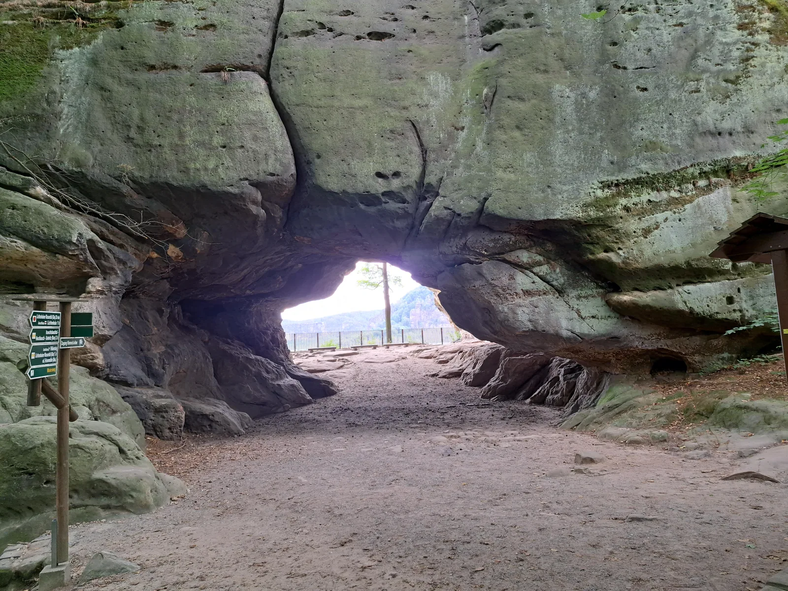 The Kuhstall rock arch from inside, with its sandstone ceiling and a view out to the viewpoint, Saxon Switzerland National Park